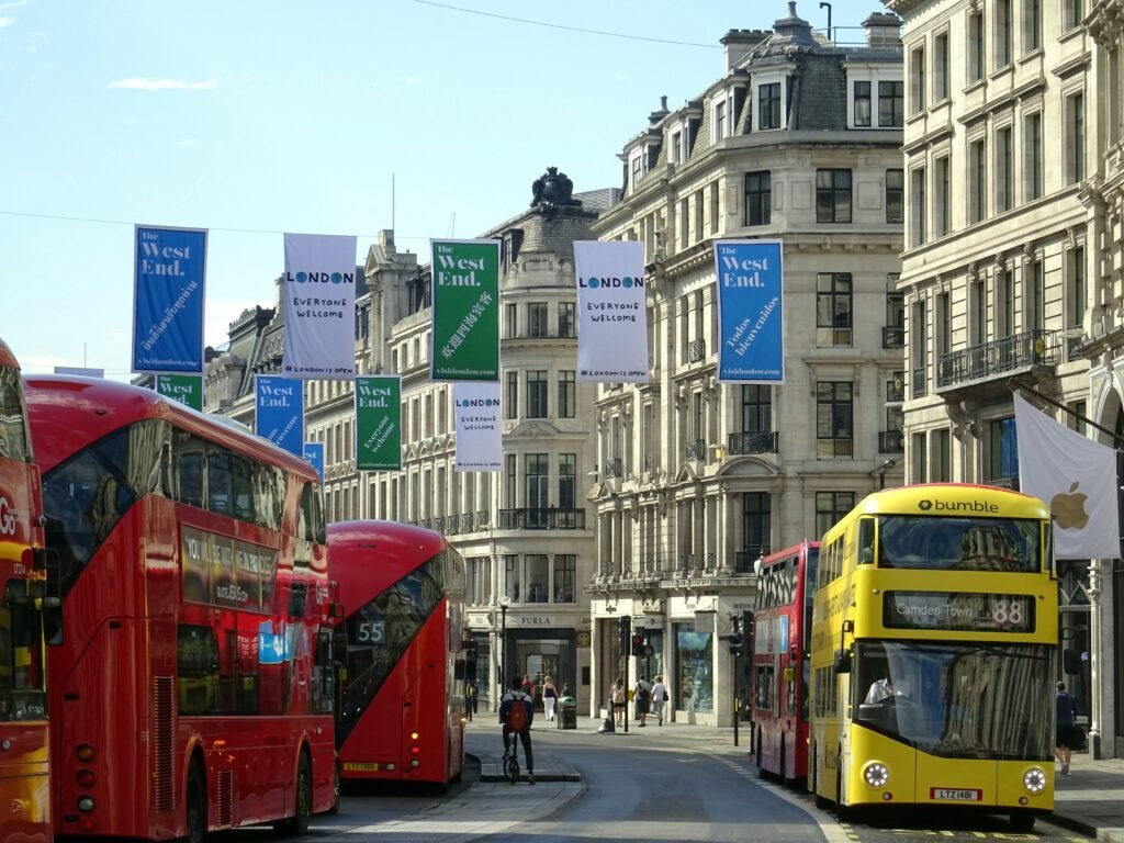 Street view of London's West End featuring iconic red double-decker buses and classic architecture.