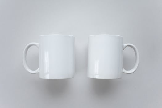 Simple white coffee mugs on a flat surface, perfect for mockup designs.